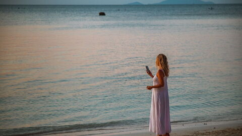 Vrouw in telefoongesprek op strand